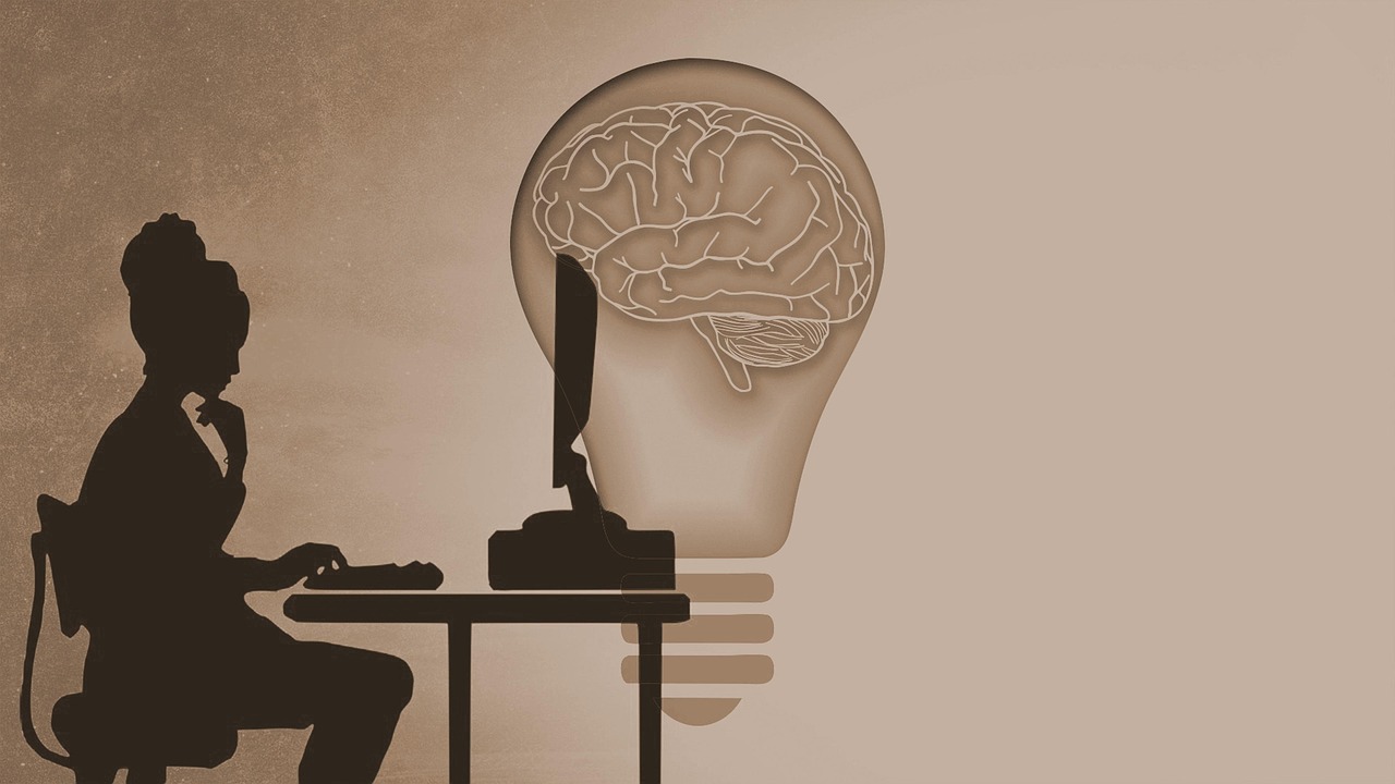 Kobieta siedząca przy komputerze a przed nią symbol żarówki z wpisanym w nią mózgiem